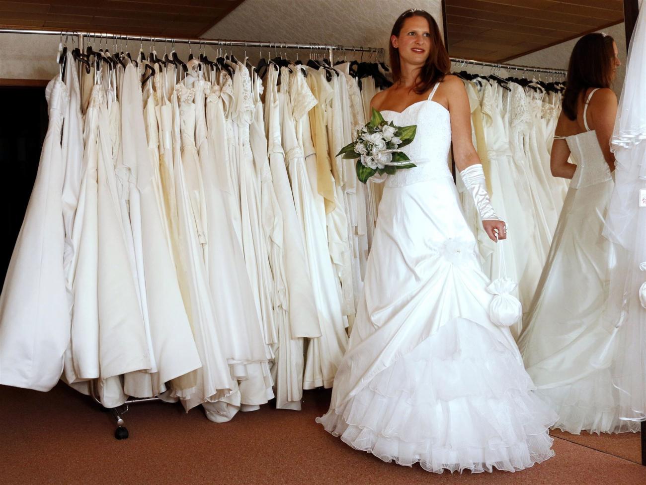 Eine Frau in einem weißen Brautkleid in einem Geschäft voller Hochzeitskleider.