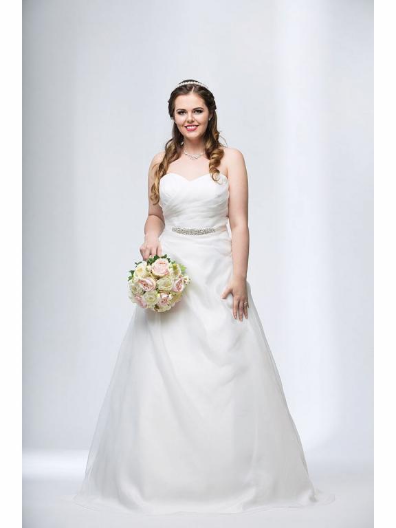 Eine lächelnde Braut in einem weißen Hochzeitskleid, die einen Blumenstrauß hält.