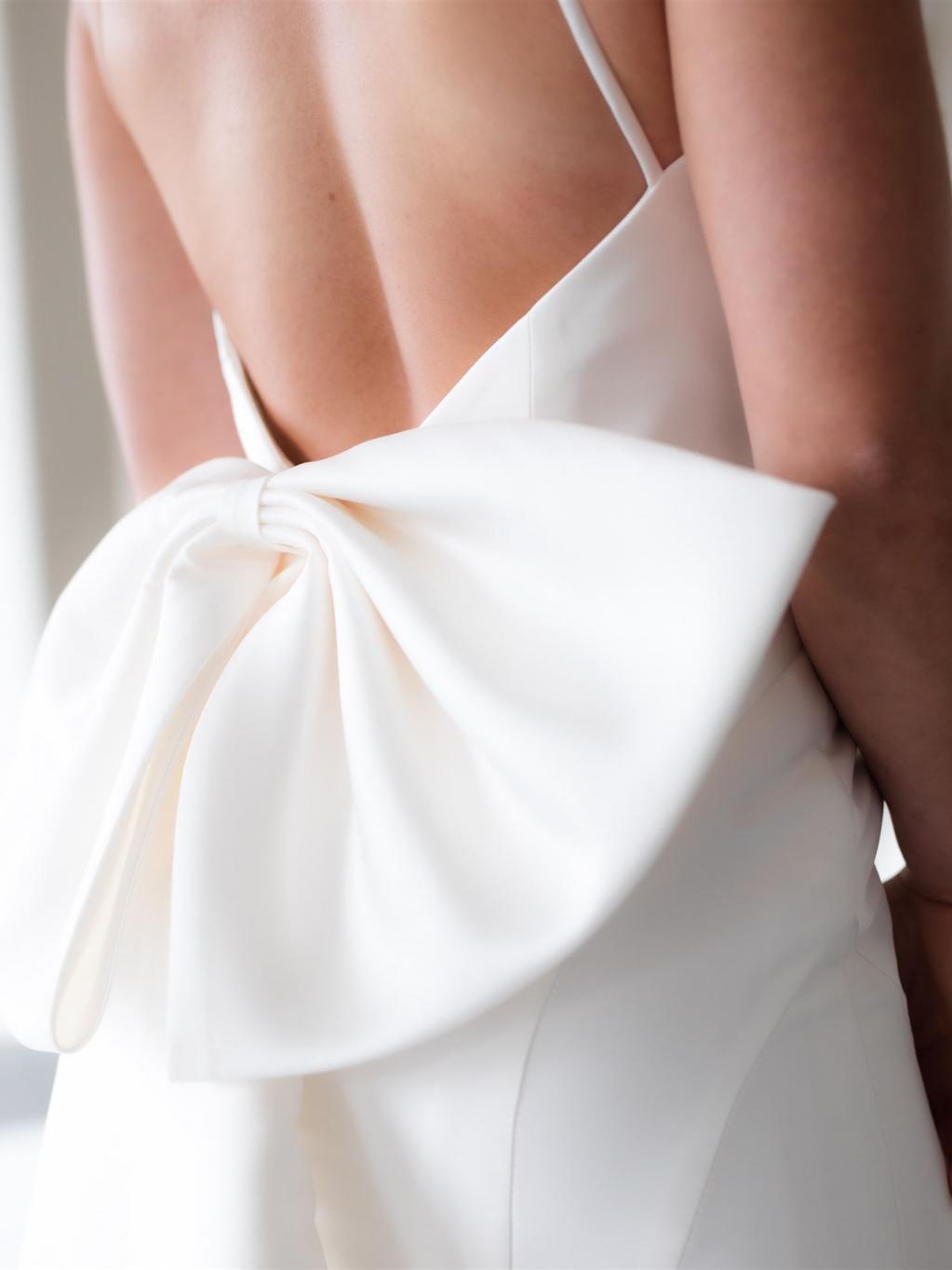 Rückansicht eines eleganten weißen Kleides mit einer großen, dramatischen Schleife.