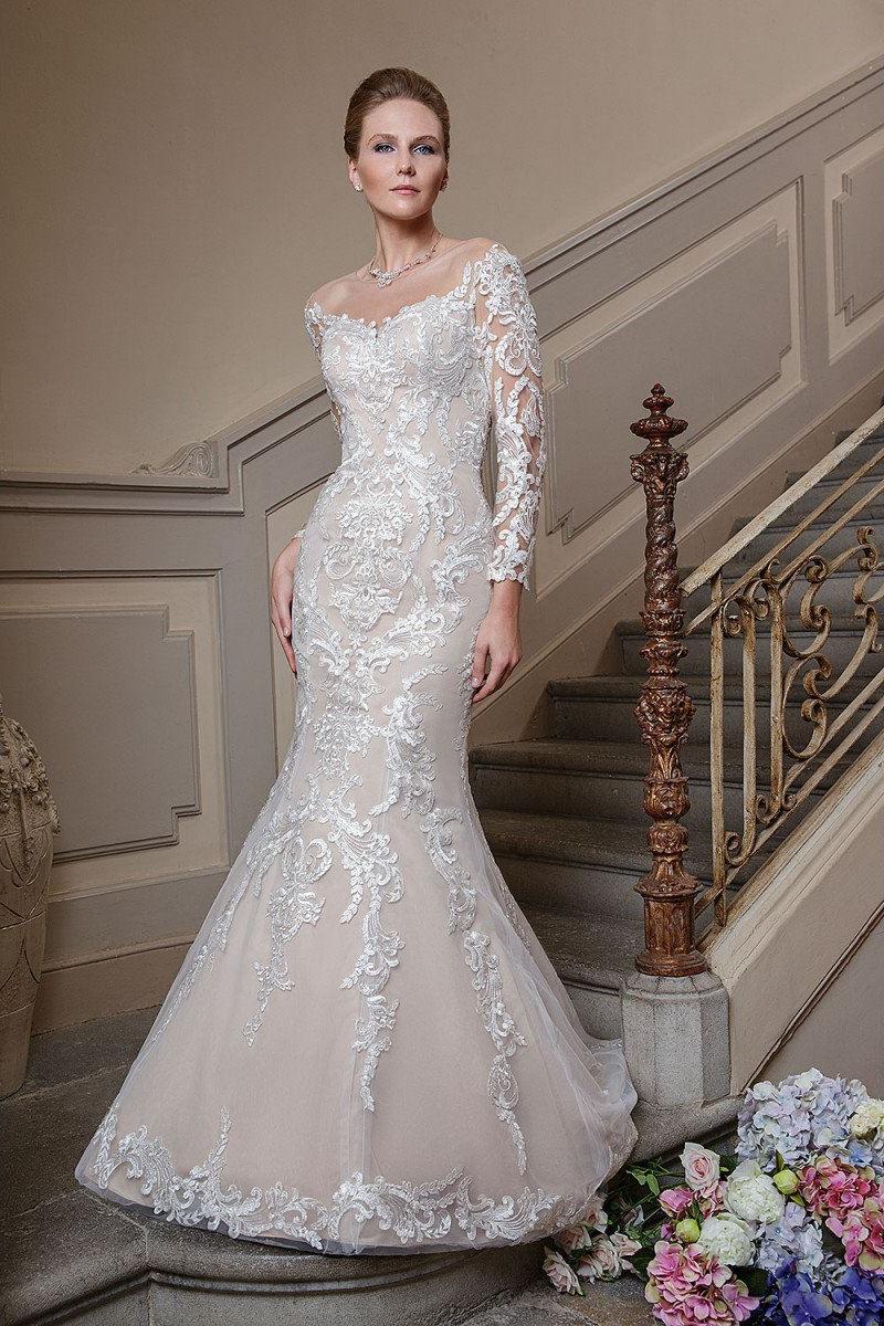 Eine Frau in einem langen, weißen Brautkleid vor einer prunkvollen Treppe.
