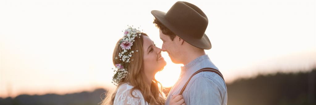 Eine junge Braut und ein Bräutigam mit Hut vor dem Horizont